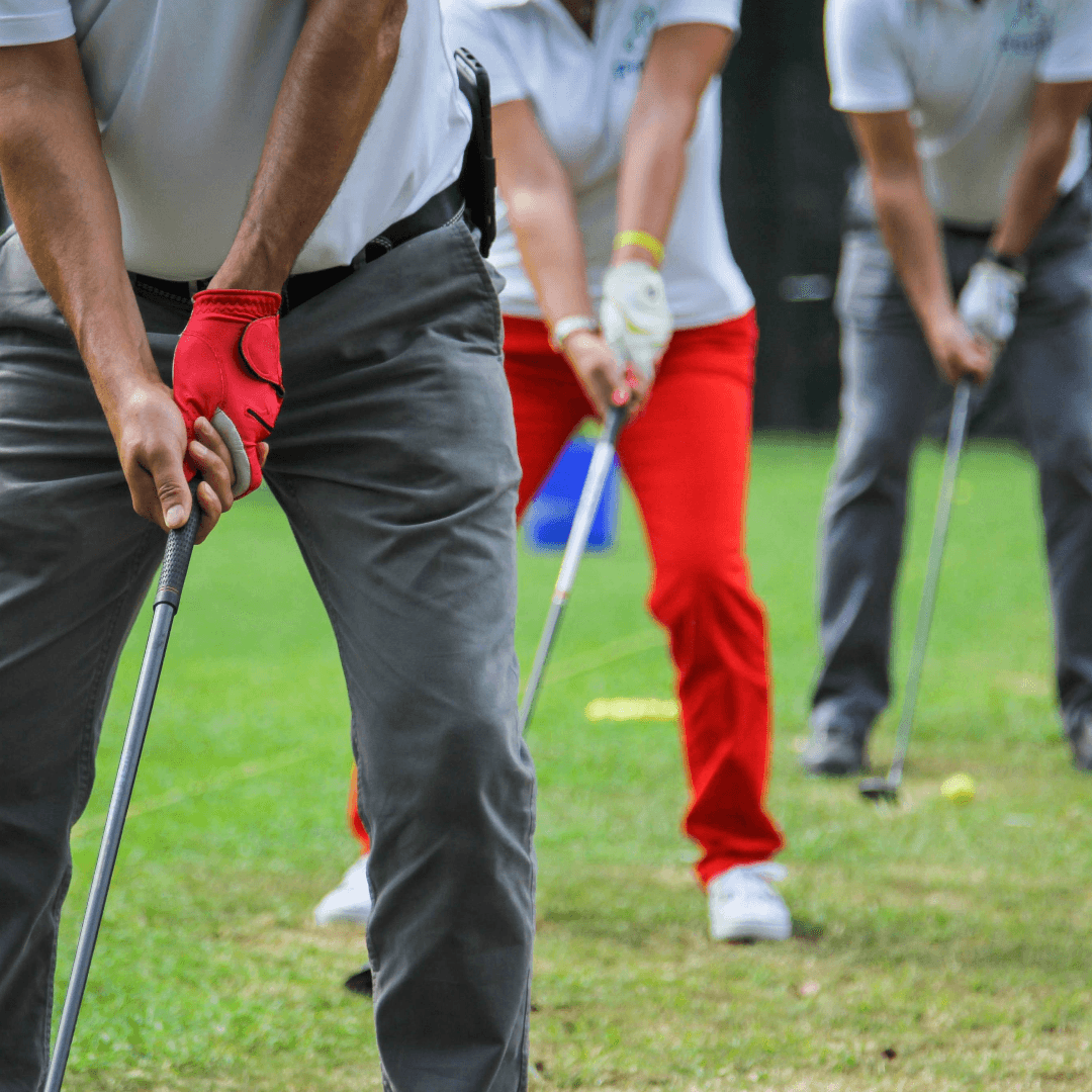 Three Prentis Golf students in a row at address with their clubs on a grass practice range